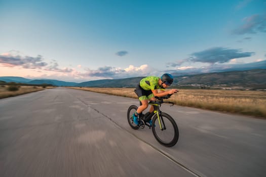 Triathlete riding his bicycle during sunset, preparing for a marathon. The warm colors of the sky provide a beautiful backdrop for his determined and focused effort