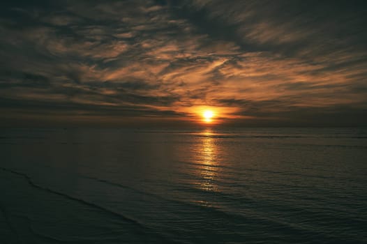 Sunset on the beach by the sea. Gentle waves. Sparkling water. The island of Poel on the Baltic Sea. Nature photo from the coast