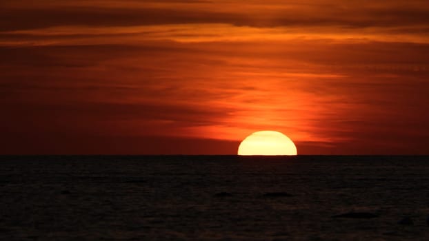 Sunset on the horizon of the Baltic Sea. Romantic evening atmosphere by the sea. Orange sun sinks into the water. Landscape photo
