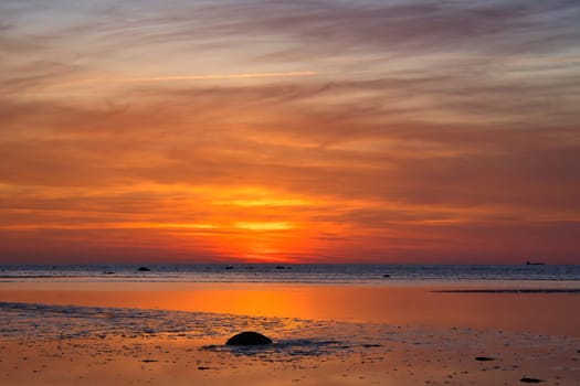 Sunset, illuminated sea. Sandy beach in the foreground. Light waves. Poel island on the Baltic Sea. Nature photo from the coast
