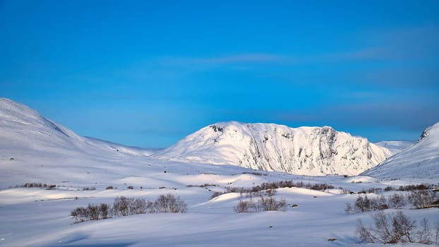 Norwegian high mountains in the snow. Mountains covered with snow. Snow-covered landscape in Scandinavia