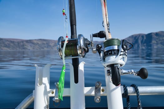 Fishing boat with fishing rod and reels off mountains in the Norwegian fjord landscape. Crystal clear water in Scandinavia