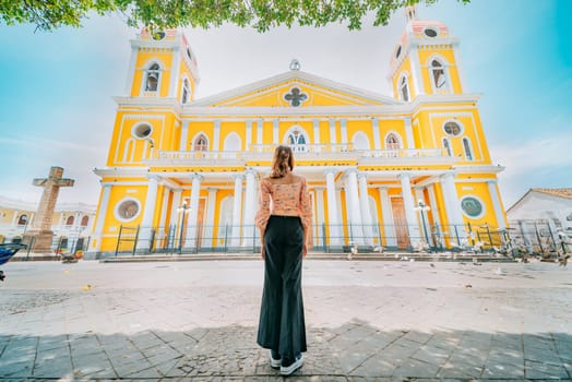 Rear view of a tourist woman in front of a cathedral in a tourist square. Back view of a beautiful tourist in the tourist plaza of Granada, Nicaragua