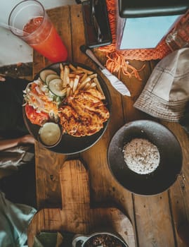 Top view of traditional roast chicken with french fries and salad served on wooden table