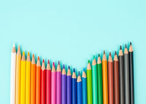 Color pencils collection in a row, back to school, drawing supplies, blue background with copy space