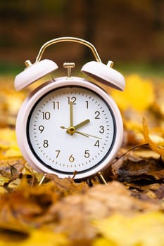 Alarm clock with autumn foliage, end of daylight saving time in fall, winter time changeover