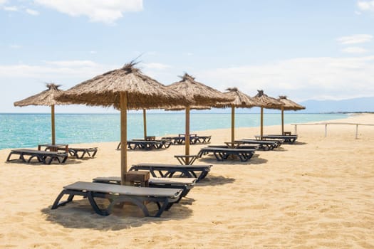 Le Barcarès, France - May 22, 2024: empty sun loungers and beach umbrellas at the coastline of the Mediterranean sea
