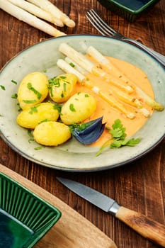 Vegan food, new boiled potatoes and white asparagus on rustic wooden table.