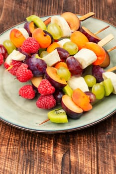 Fruit skewers made from fresh fruits on skewers on a wooden table.