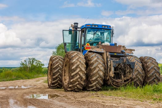 Blue New Holland tractor with double wheels standing near agricultural field at hot sunny day in Tula, Russia - June 4, 2022