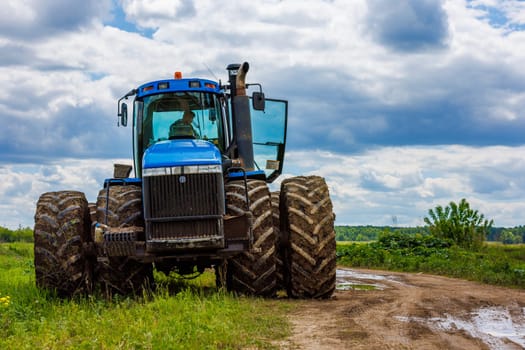 Blue New Holland tractor with double wheels standing near agricultural field at hot sunny day in Tula, Russia - June 4, 2022