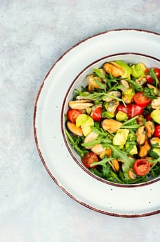 Plate with vitamin salad of mussels, arugula, tomato and avocado. Top view.