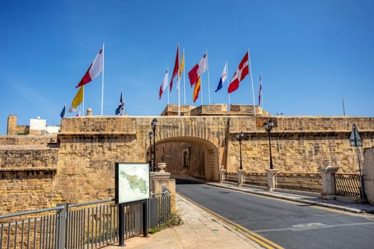Gate of Provence Birgu and city fortification with Maltese flags. Beautiful view of entrance of ancient city Birgu, part of the Three Cities of Malta. Cultural heritage of Malta