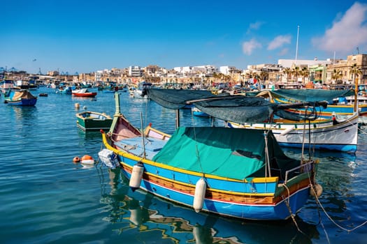 Traditional eyed colorful boats Maltese Luzzu in the turquoise blue water in the Harbor of Mediterranean fishing village Marsaxlokk, Cultural heritage of Malta.