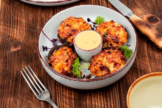 Stuffed mushrooms, champignon mushroom caps filled with vegetables on rustic wooden table. Healthy food