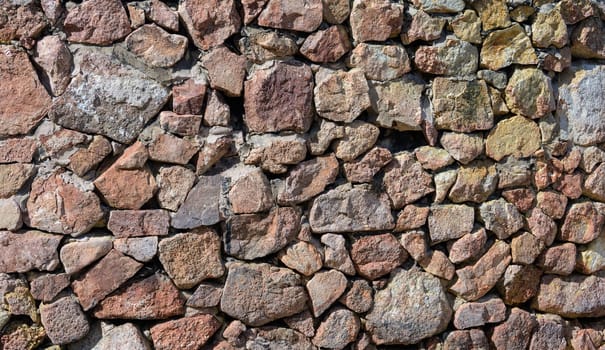 Stone wall background built from a variety of shapes and sizes and fitted together to create a strong and stable structure.
