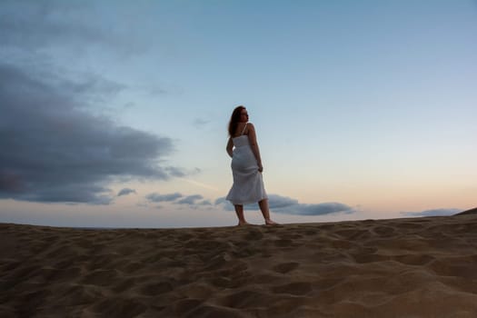 Young woman stands with her back in the sand dunes