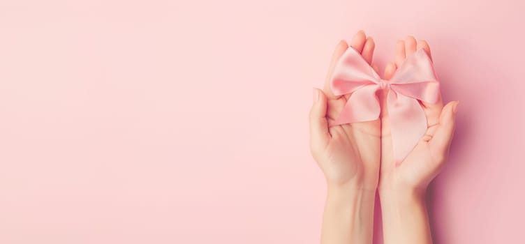 Holding a pastel pink bow in the hand, festive background, gift for holiday, birthday, christmas, valentines day, mother day