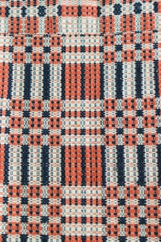 Close-up of a woven textile with a geometric pattern in red, blue, and white colors.