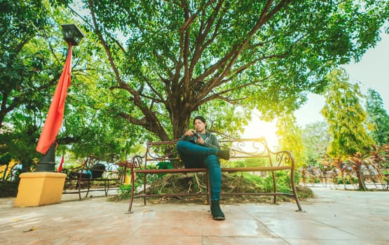 Photographer sitting on a bench checking his camera. Male photographer checking dslr camera sitting on a bench