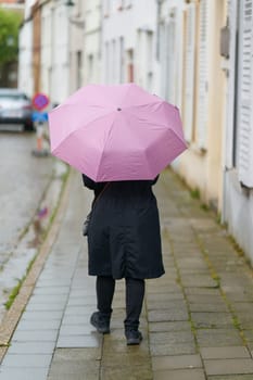 Woman with umbrella in rainy weather in the old town of Bruges in Belgium