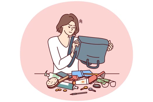 Puzzled woman shakes out contents of bag on table trying to find wallet with money or mobile phone. Girl is embarrassed because of mess in bag causing inconvenience and loss of wallet