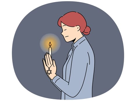 Praying jewish woman with star of david and burning candle in hand for international holocaust remembrance day concept. Jewish praying girl turns to god standing in synagogue and reading prayers