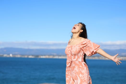 Excited woman screaming to the air on the beach