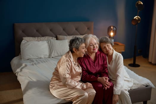 Portrait of excited aged female friends on pension gathering for hen-party at home on weekends. Relaxation and carefree fun time on retirement