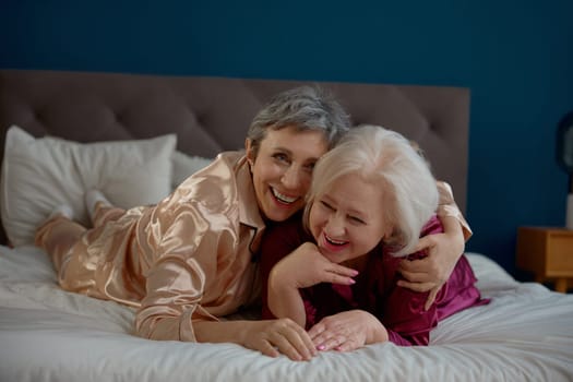 Excited laughing two elderly women enjoying time together during pajama party at home. Happy retirement