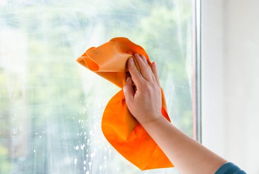 Employee cleaning window pane, wipe with a cloth, dry the water and soap, swab dusty and dirty glass, housework