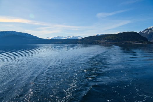 Norwegian fjord landscape. Blue water overlooking mountains with snow-covered peaks. Scandinavian nature from the north