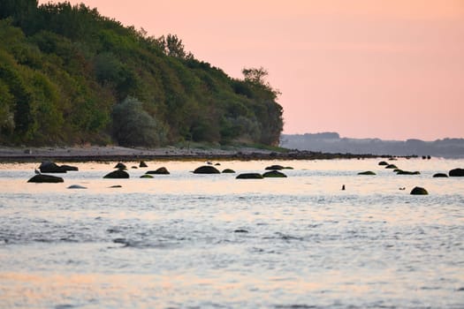 Sunset, illuminated sea. Sandy beach in the foreground. Light waves. Poel island on the Baltic Sea. Nature photo from the coast