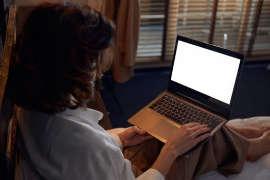 Businesswoman working online using laptop while resting with comfort and tranquility in bed at hotel room