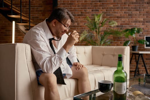 Frustrated drunk businessman working online having troubles with alcohol. Male boss entrepreneur discussing digital project remotely during virtual business meeting. Career and alcoholism