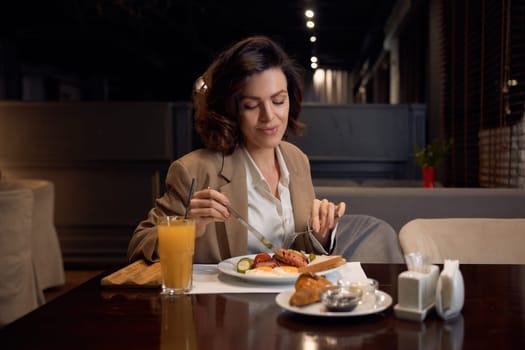 Attractive smiling businesswoman eating lunch at hotel restaurant. Break time during business trip