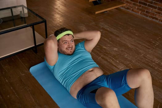 Funny fat man doing abs sport training at home. Funny hardworking guy exercising burning calories