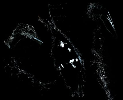 Long stream of fresh transparent water isolated on black background. Splash and drops