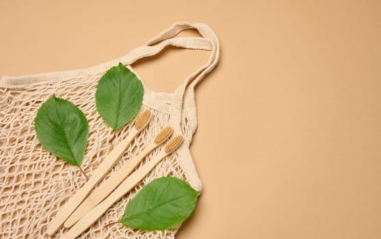 Wooden toothbrushes and textile wicker bag on a brown background, top view