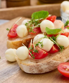 Round mozzarella, cherry tomatoes and microgreens on a piece of white bread, a healthy sandwich