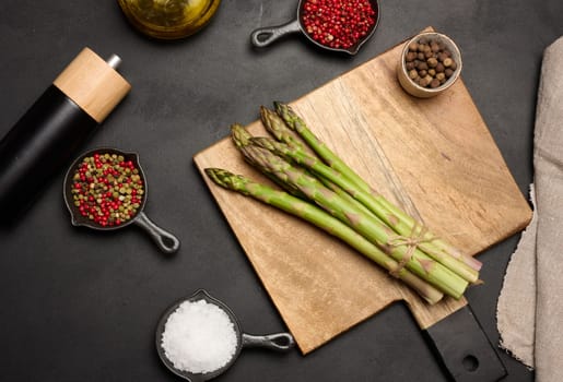 Fresh green asparagus sprouts on a black wooden background. View from above