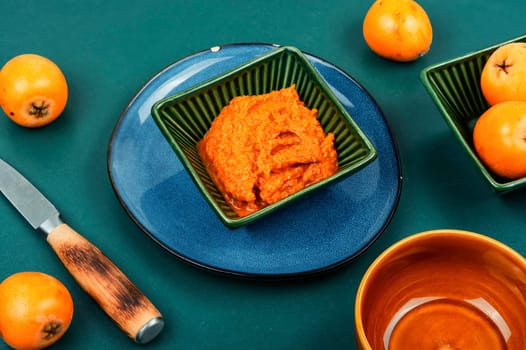 Cooking fresh vegan medlar or loquat fruit sauce in glass bowl.