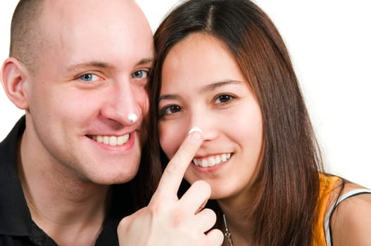 Head and shoulder portraits of a young couple with dabs of cream on their noses looking happily into the camera.