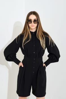 Young woman posing in black skort and blouse with loose sleeves over white background