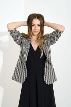 Portrait of a joyful smiling young woman in a plaid jacket holding both hands behind her head