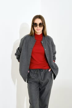Studio portrait of young cute woman wearing sportswear and sunglasses on white background