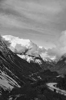 Norwegian landscape. Road leads through a mountain gorge that descends from the glacier in black and white. Rough nature in Scandinavia. Landscape photo from the north