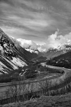 Norwegian landscape. The road leads through a mountain gorge that descends from the glacier. Rough nature in Scandinavia. Landscape photo from the north