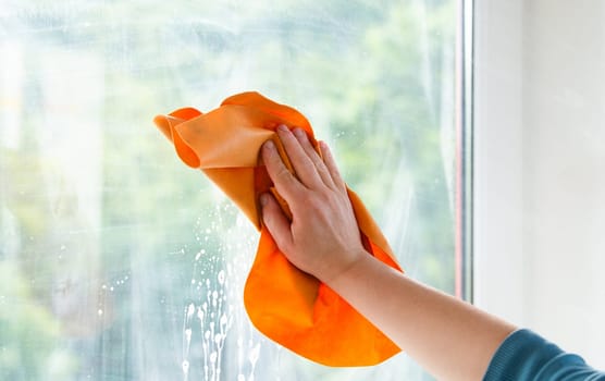 Employee cleaning window pane, wipe with a cloth, dry the water and soap, swab dusty and dirty glass, housework