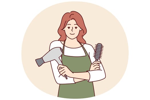 Woman professional hairdresser from barbershop holding comb and hair dryer to care for client hairstyle. Girl working as hairdresser in beauty salon stands with arms crossed and looks at camera